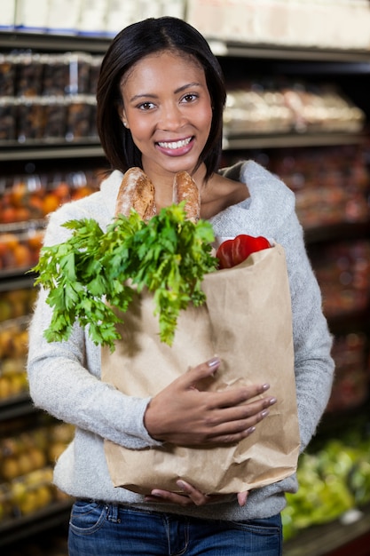 Portrait de femme souriante tenant un sac d'épicerie