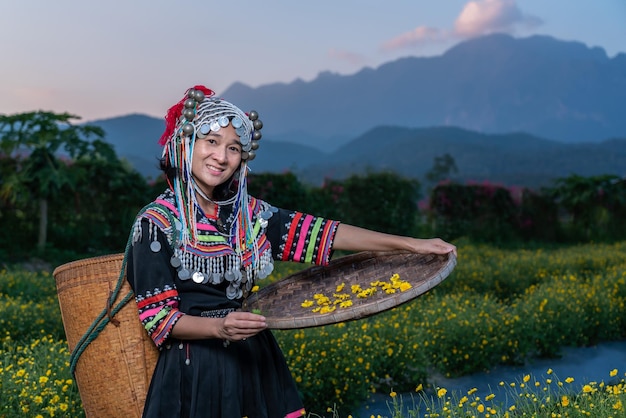 Portrait d'une femme souriante en vêtements traditionnels tenant un panier en osier alors qu'elle se tient dans une ferme