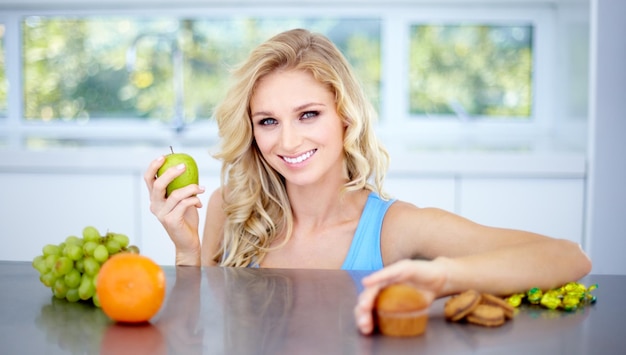 Portrait de femme sourire et fruits dans une alimentation saine nutrition ou fibres dans un régime sur la table de la cuisine