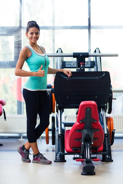 Portrait de femme sportive montrant le pouce vers le haut dans la salle de fitness