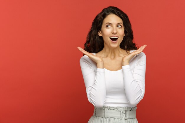 Portrait de femme surprise avec la bouche grande ouverte sous le choc, regarde de côté pour copier l'espace pour la publicité