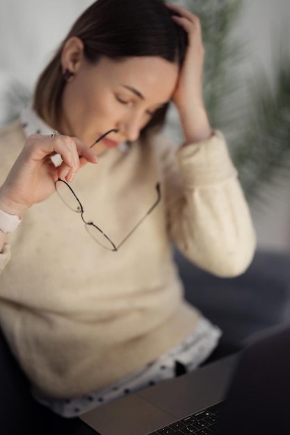 Portrait d'une femme tenant des lunettes d'une main et sa tête fatiguée avec d'autres Stress