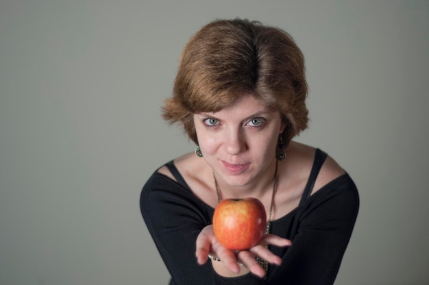 Portrait d'une femme tenant une pomme sur un fond gris