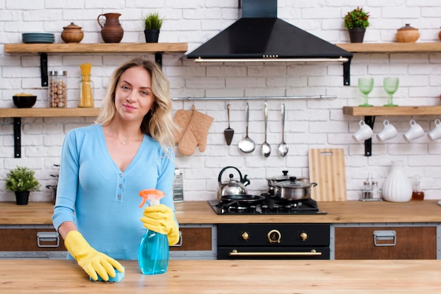 Portrait, femme, tenue, éponge, détergent, vaporisateur, debout, cuisine