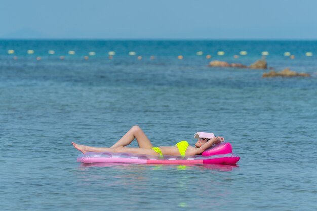 Portrait de femme thaïlandaise en bikini sur un gonflable rose sur l'eau à la plage