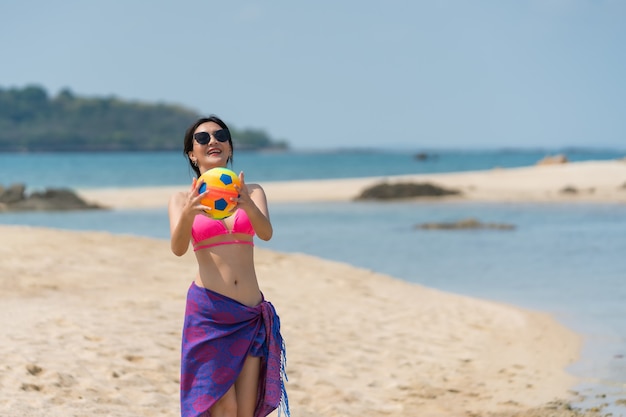 Portrait de femme thaïlandaise en bikini jouant avec un ballon à la plage