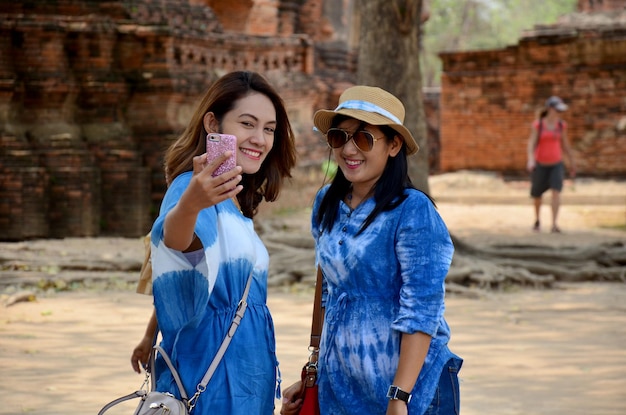 Portrait de femme thaïlandaise et prendre des photos par téléphone portable au Wat Mahathat à Ayutthaya en Thaïlande