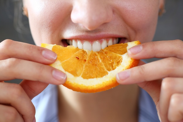 Portrait de femme tient dans sa main une tranche d'orange