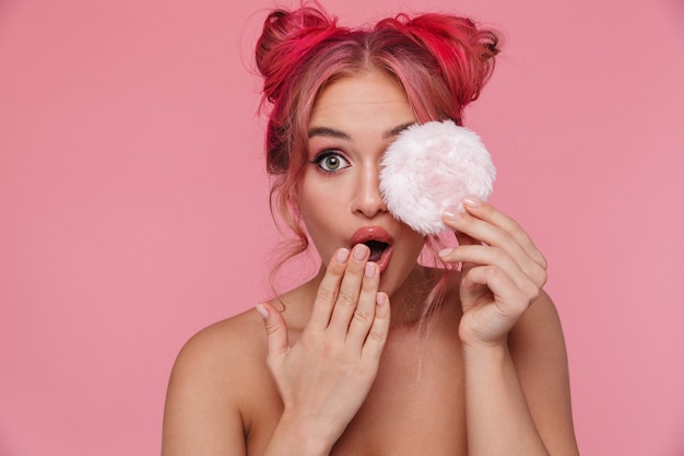 Portrait d'une femme torse nu excitée avec une coiffure colorée tenant une houppette