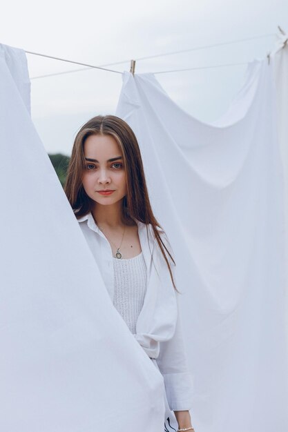 Portrait d'une femme tranquille avec une beauté naturelle regardant la caméra près du linge blanc dans la nature