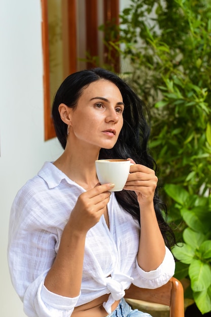 Portrait d'une femme ukrainienne souriante buvant un capuccino chaud et regardant la caméra