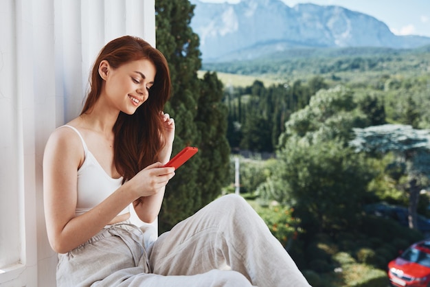 Portrait femme utiliser le téléphone regarde l'écran dans un hôtel confortable une vue dégagée sur la vue sur la montagne