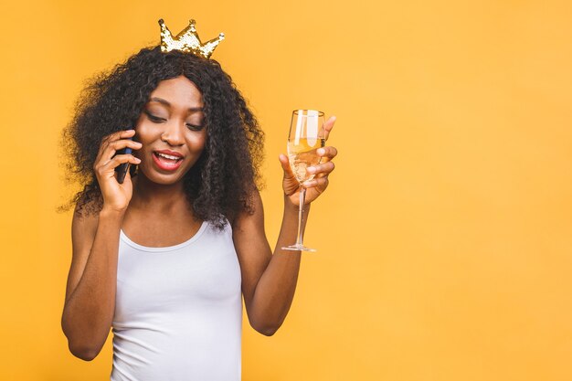 Portrait de femme avec verre de champagne et couronne d'or, parler au téléphone