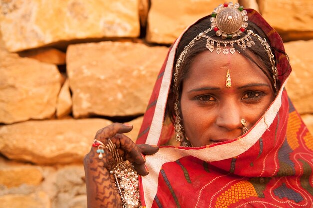 Photo portrait d'une femme en vêtements traditionnels contre un mur de pierre