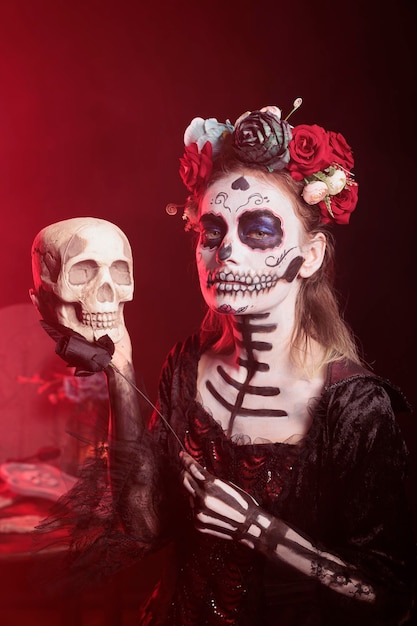 Portrait d'une femme vêtue du costume du Jour des Morts posant avec un crâne à la main