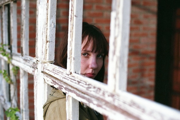 Photo portrait d'une femme vu à travers le cadre d'une fenêtre