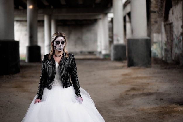 Photo portrait de femme zombie avec visage crâne peint sous un pont.