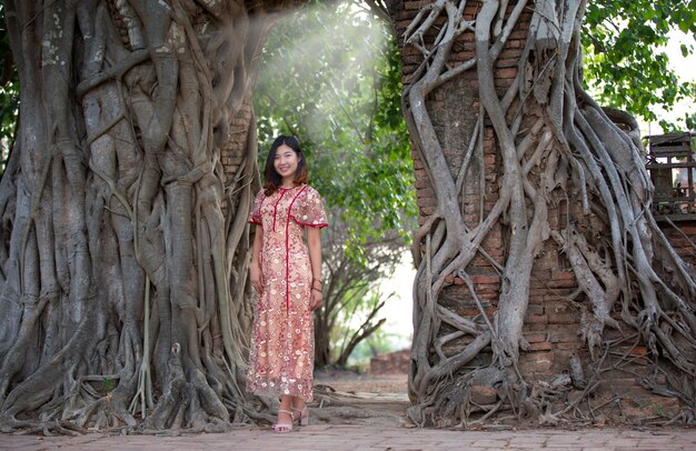 Portrait de femmes asiatiques debout contre le mur de briques avec des racines d'arbres.