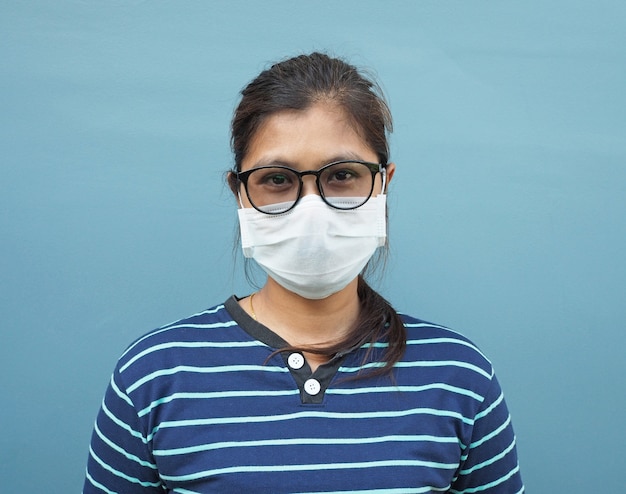 Portrait De Femmes Asiatiques Portant Des Lunettes Et Des Masques De Protection Sur Fond Bleu.