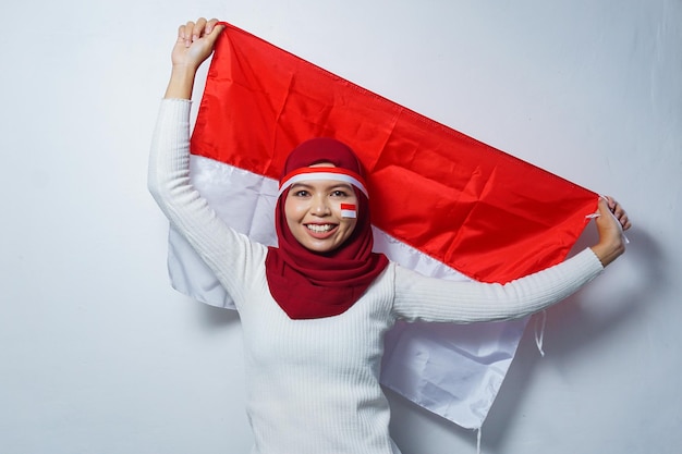 Le portrait des femmes musulmanes asiatiques célèbrent le jour de l'indépendance indonésienne tenant le drapeau rouge et blanc
