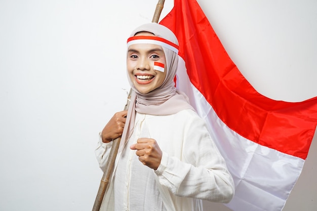 Le portrait des femmes musulmanes asiatiques célèbrent le jour de l'indépendance indonésienne tenant le drapeau rouge et blanc