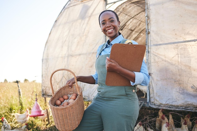 Photo portrait de ferme et femme noire avec presse-papiers et œufs dans une ferme pour une agriculture durable et une chaîne d'approvisionnement en campagne sourire du visage et agriculteur avec liste de contrôle ou gestion des produits avicoles