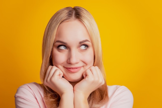 Portrait d'une fille adorable inspirée par un rêve, les joues des poings ressemblent à un espace vide sur fond jaune