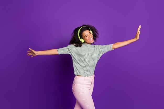 Portrait de fille afro-américaine écouter de la musique utiliser un casque vert chanter chanson danse