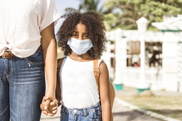 Portrait d'une fille afro-américaine avec sac à dos portant un masque Retour à l'école et nouvelle normalité