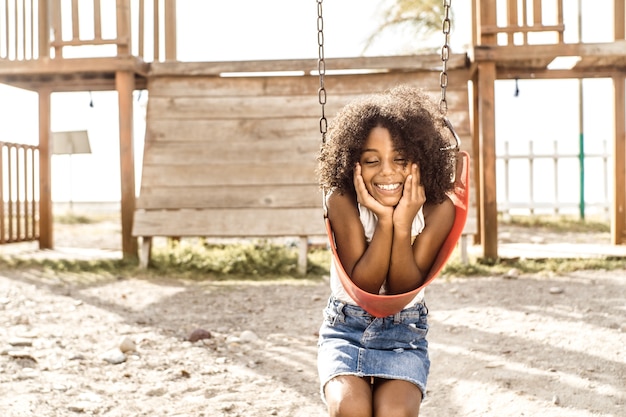 Portrait d'une fille afro-américaine souriante regarde le concept d'enfance et de bonheur de la caméra