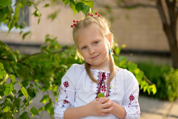 Portrait d'une fille d'âge préscolaire avec des fleurs dans une chemise brodée ukrainienne Viorne dans les cheveux