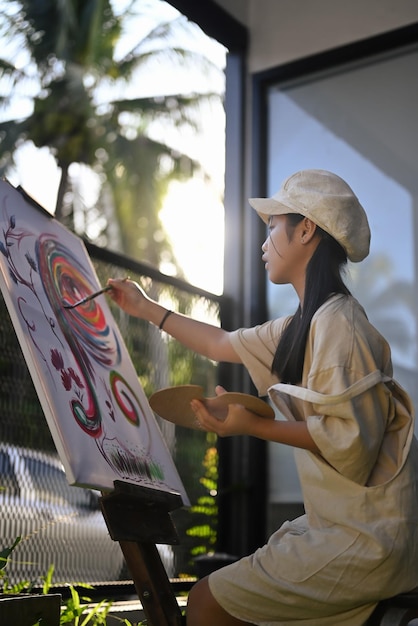 Portrait d'une fille asiatique peignant sur toile avec de l'eau de couleur en classe d'art