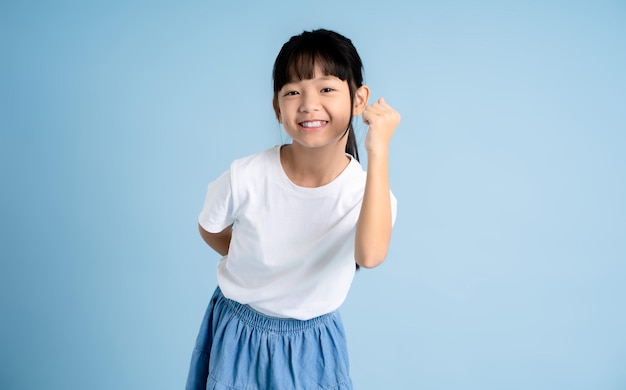 Portrait d'une fille asiatique posant sur un fond bleu