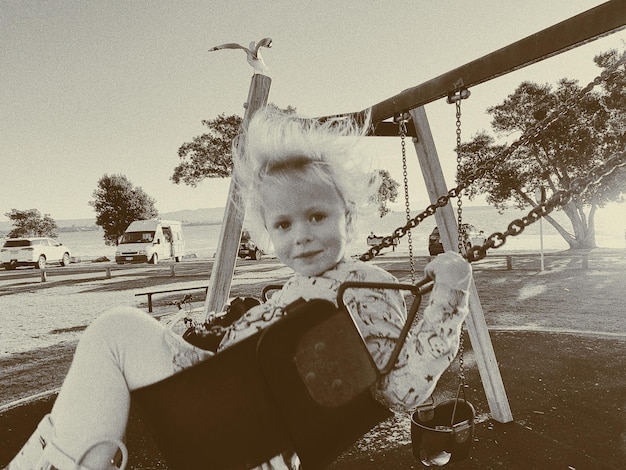 Portrait d'une fille assise sur une balançoire dans un parc