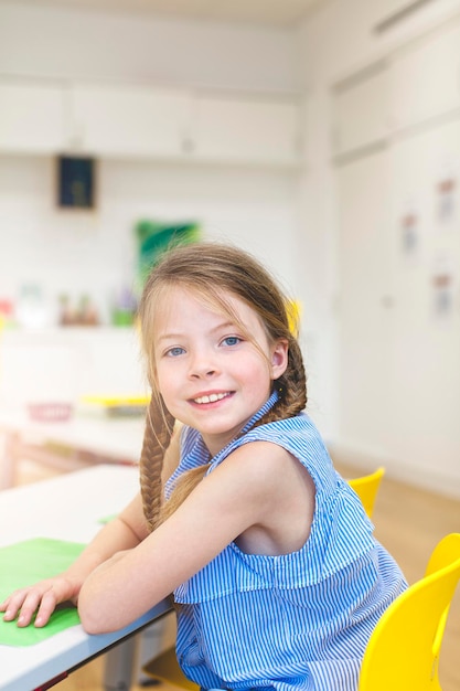 Portrait d'une fille assise à un bureau dans une salle de classe