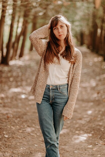 Portrait d'une fille aux cheveux bruns dans un cardigan lors d'une promenade dans la forêt