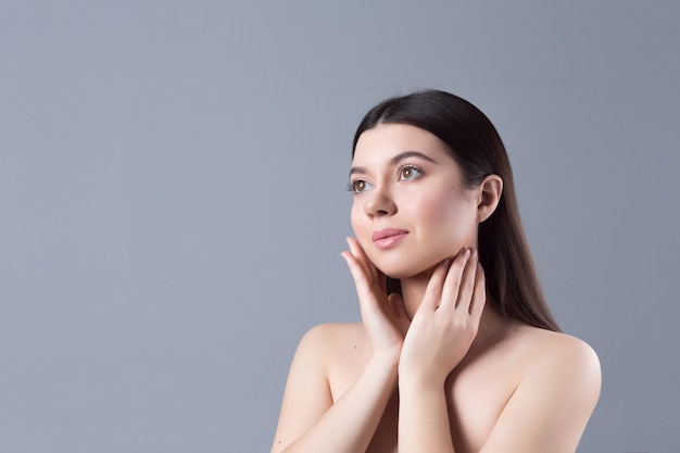 Portrait d'une fille de beauté avec un maquillage nude naturel touchant son visage. Spa, soins de la peau