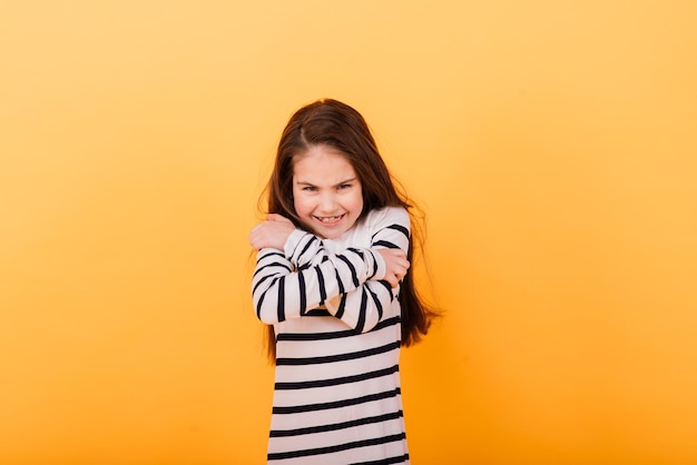 Portrait d'une fille belle et confiante montrant des émotions et des pouces vers le haut isolés sur jaune