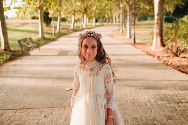 Portrait d'une fille blonde aux cheveux bouclés vêtue d'une robe de communion