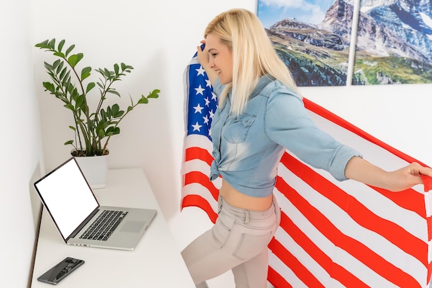 Portrait d'une fille blonde avec drapeau USA avec ordinateur portable.