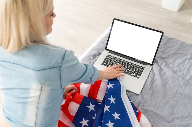 Portrait d'une fille blonde avec drapeau USA avec ordinateur portable.