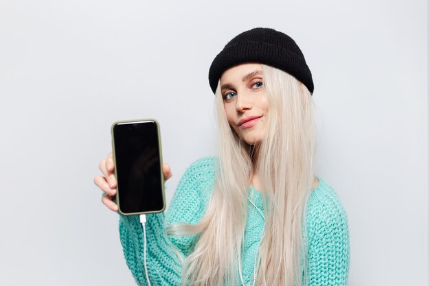 Portrait d'une fille blonde joyeuse avec un smartphone à la main