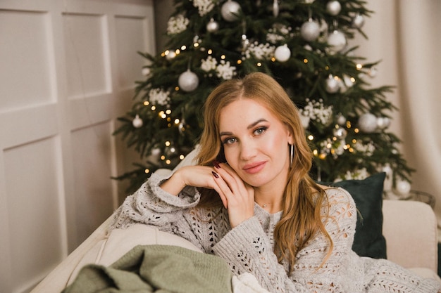 Portrait d'une fille sur un canapé dans le contexte d'un arbre de Noël