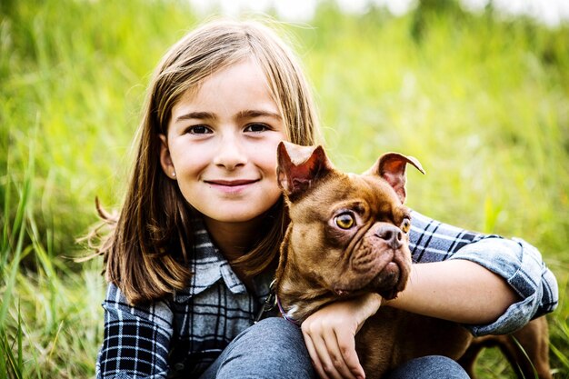 Photo portrait d'une fille avec un chien assis sur un champ