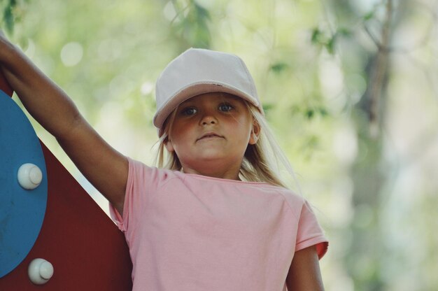 Photo portrait d'une fille debout près d'un équipement de jeu en plein air contre des arbres