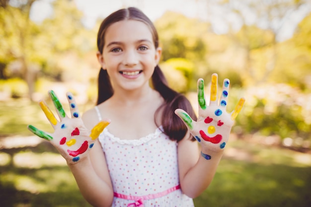 Portrait d'une fille avec du maquillage montrant ses mains peintes