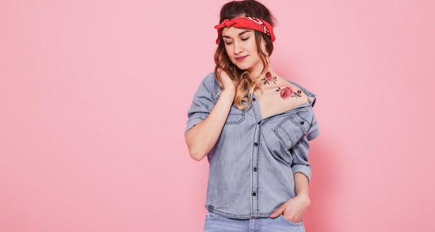 Portrait d'une fille élégante en vêtements en denim sur un mur rose