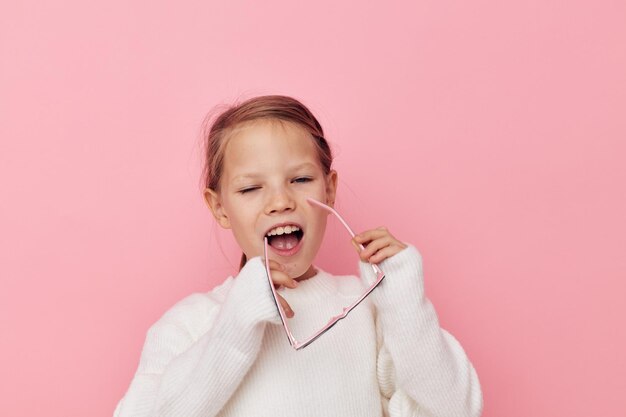 Portrait d'une fille enfant souriante heureuse dans un pull blanc et des lunettes fond isolé