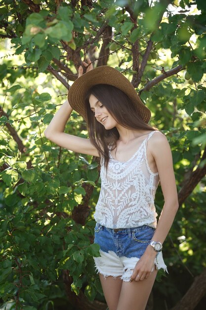 Le portrait de fille d'été dans les verts. La belle jeune femme brune profite de la fraîcheur du jardin d'été.