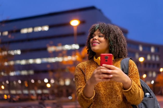 Portrait d'une fille ethnique noire tôt le matin allant à l'université sur le chemin du retour à l'école en parlant au téléphone